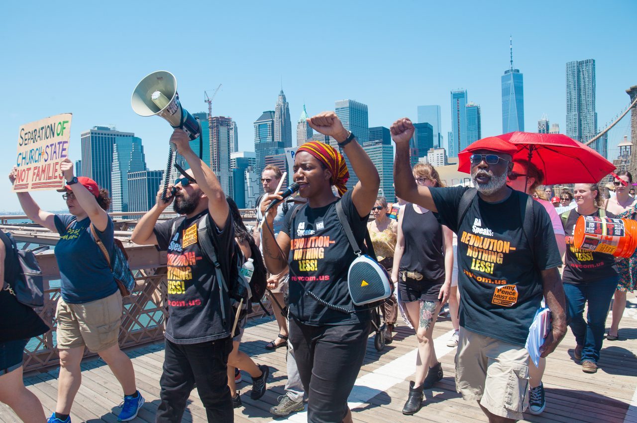 6/30/2018. New York City - March: “Families Belong Together.” People wearing t-shirts that reads: 'Revolution -nothing less!" People crossing the Brooklyn Bridge in support of refugee families. People’s protectors are marching from Foley Square in Manhattan to Cadman Plaza in Brooklyn. Credit: Photo by Javier Soriano/LoveIsAmor.com