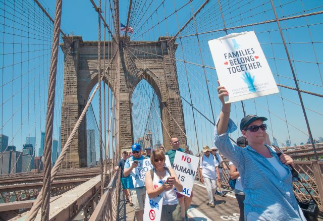 6/30/2018. New York City - March: “Families Belong Together.” Woman with a sign that reads: "Families belong together." People crossing the Brooklyn Bridge in support of refugee families. People’s protectors are marching from Foley Square in Manhattan to Cadman Plaza in Brooklyn. Credit: Photo by Javier Soriano/LoveIsAmor.com