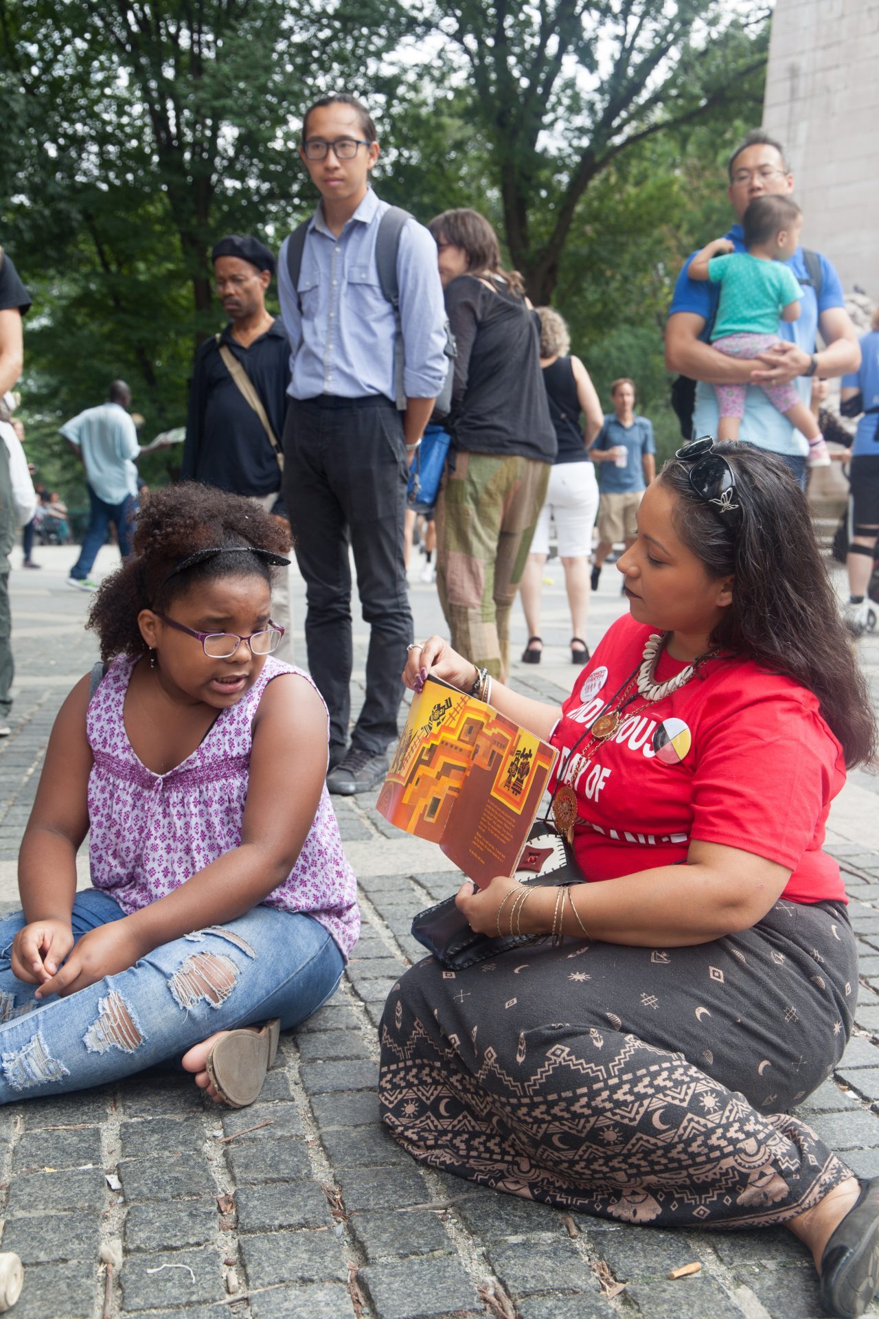 Sunday, October 7th, 2018. Columbus Circle. West 59th Street and Central Park West. Manhattan, New York City - Girl reading at the 11th Annual Indigenous Day of Remembrance. Credit: Photo by LoveIsAmor.com