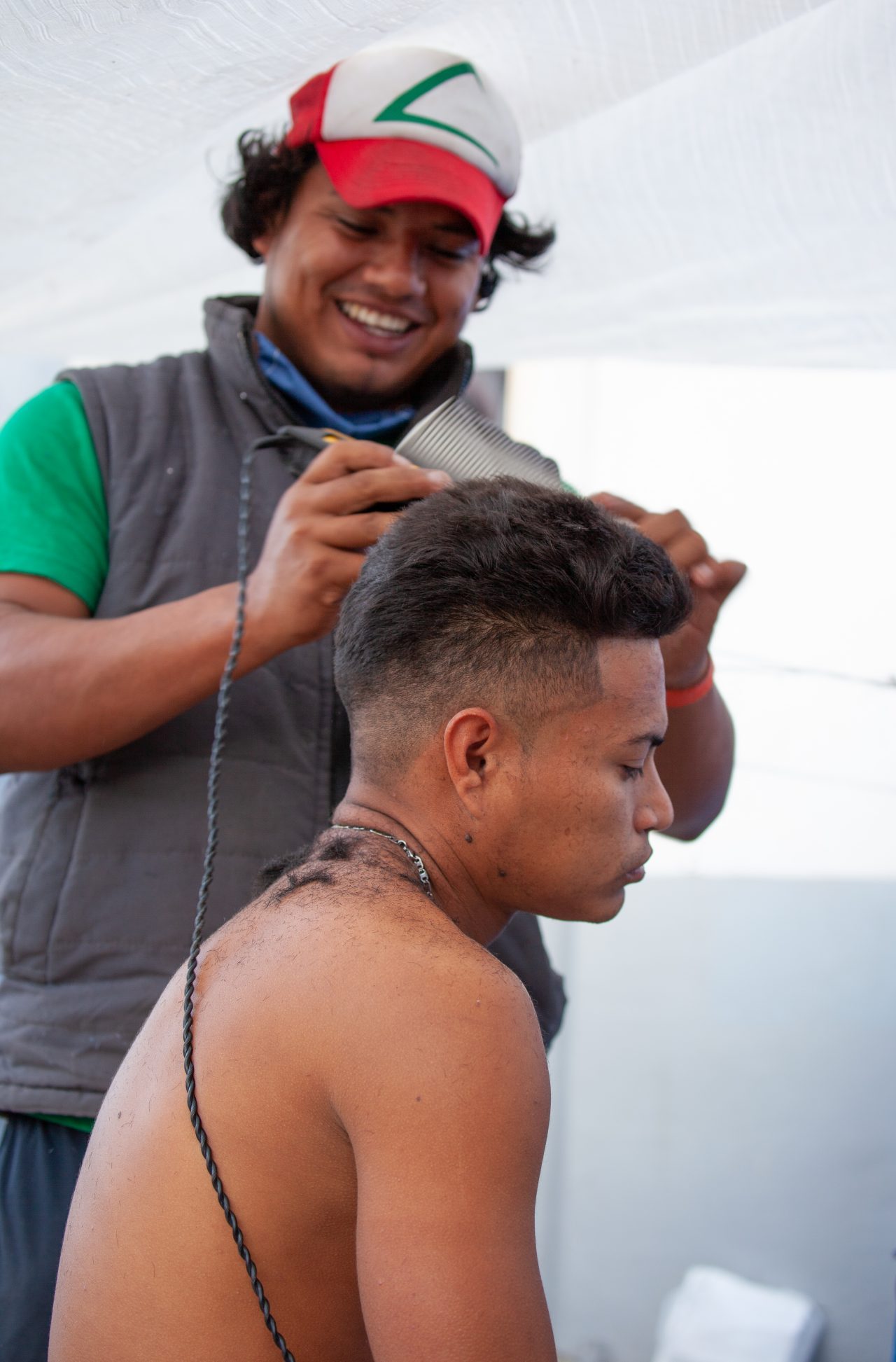 Tijuana, Baja California. Mexico. Tuesday, November 27th, 2018. A refugee man getting a haircut by another refugee man at Unidad Deportiva Benito Juárez (an improvised shelter for the caravans of immigrants). Refugees are fleeing violence in their countries in Central America. They want to apply for asylum in the United States of America. Credit: Photo by LoveIsAmor.com