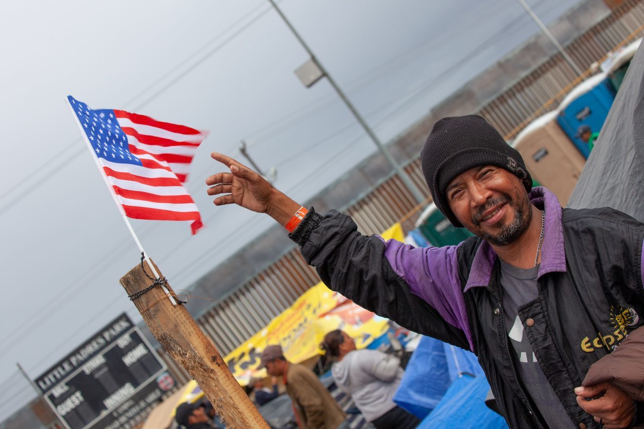 Tijuana, Baja California. Mexico. Thursday, November 29th, 2018. Refugee man from Honduras with the American flag at Unidad Deportiva Benito Juárez (an improvised shelter for the caravans of immigrants). Refugees are fleeing violence in their countries in Central America. They want to apply for asylum in the United States of America. They were told they have to wait more than a month to apply for asylum. Credit: Photo by LoveIsAmor.com