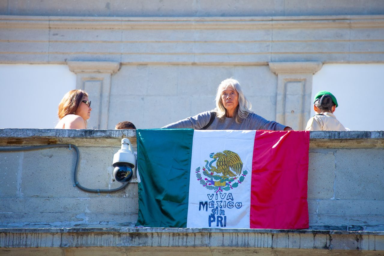 Mexico City, Mexico. Saturday, December 1, 2018. Woman with the Mexican flag at the house where Mexican Presidents used to live. The flag reads: "Viva México sin PRI." The "Official Residence of Los Pinos" was the residence of the Mexican presidents. As of Saturday, December 1, 2018, it will be known as the "Los Pinos Cultural Complex." The official website says: "Los Pinos will be a completely open space for all Mexicans." Today was the inauguration of Mexican President Andrés Manuel López Obrador. People came to Los Pinos to celebrate this historic day. Credit: Photo by LoveIsAmor.com